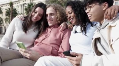 Dışarıda cep telefonu kullanan bir grup çok ırklı genç arkadaş.