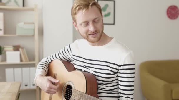Genç bir adam evde online müzik dersinde gitar çalmayı öğreniyor. — Stok video