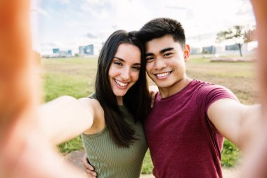 Çok ırklı genç bir çift tatilde dışarıda selfie çekiyor.