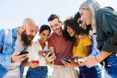 Dışarıda cep telefonu kullanırken gülümseyen bir grup mutlu insan.