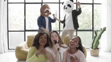 Bir grup çok ırklı insan evde karaokeyle eğleniyor.