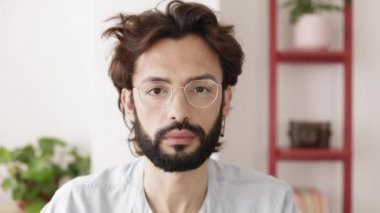 Başarılı genç girişimci evdeki kameraya bakıyor.