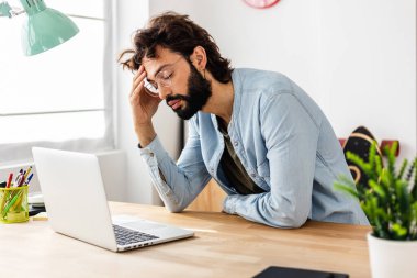 Young businessman having headache while working in home office