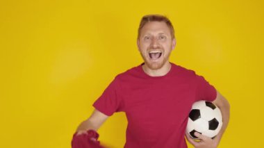 Heyecanlı futbol taraftarı sarı arka planda kutlama yapıyor