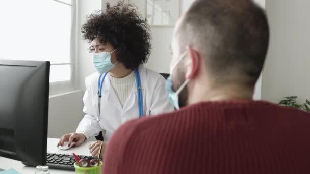 Médico e paciente em máscara facial conversando em uma consulta médica em uma clínica — Vídeo de Stock