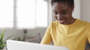 Gülümseyen Afrikalı öğrenci evde online öğrenim için dizüstü bilgisayar kullanıyor.