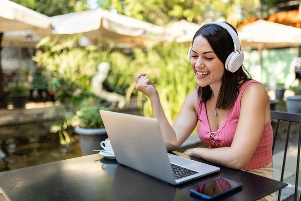 Sokakta dizüstü bilgisayarda çalışan gülümseyen kadın.