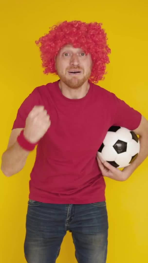 Vertikal skott av fotboll fläkt i röd enhetlig jubel över gul bakgrund — Stockvideo