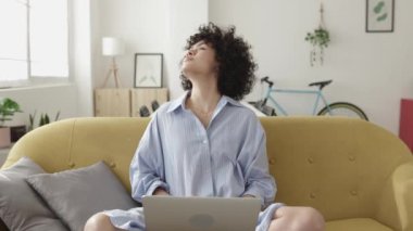 Evde dizüstü bilgisayar kullanan genç bir kadın. 