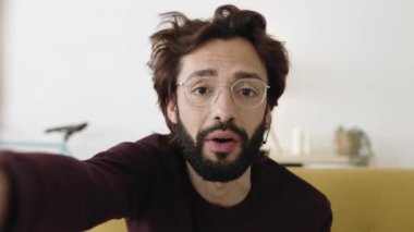 Hipster bir gencin evden cep telefonuyla görüntülü konuşması.