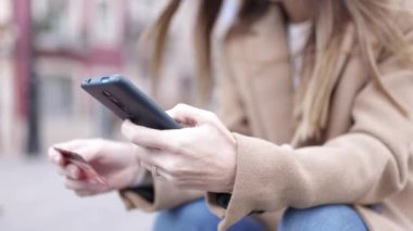 Kadın eli kapalı, elinde kredi kartı ve internetten cep telefonuyla alışveriş yapıyor.
