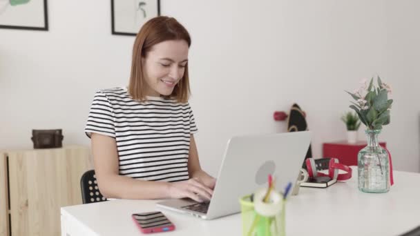 Beautiful young woman working on laptop computer from home — Vídeos de Stock