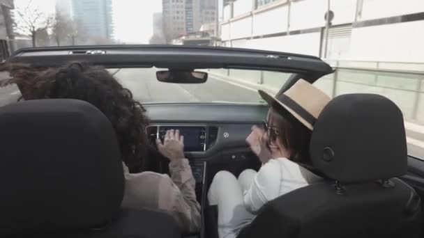 Happy young couple listening to music while driving cabriolet car in the city — Video