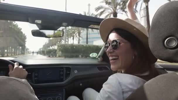 Feliz pareja joven riendo juntos mientras conducen un coche convertible en vacaciones — Vídeos de Stock