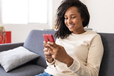 Mixed race young woman using smart mobile phone at home