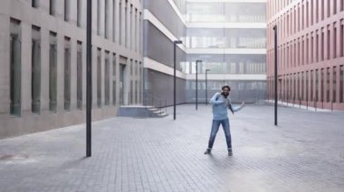 Başarılı, mutlu, modaya uyan genç adam işten sonra şehirde tek başına dans ediyor.