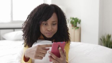 Excited happy young woman celebrating success holding mobile phone at room