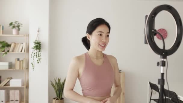Young fitness instructor streaming online class teaching yoga from home — Stockvideo