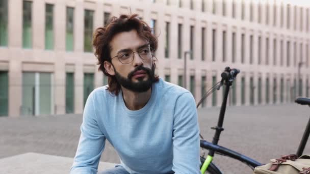 Trendy young hipster commuter man with urban bike sitting in financial district — Vídeo de stock