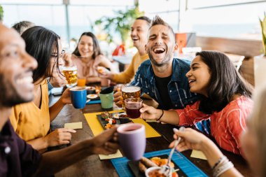 Bir grup çok ırklı genç arkadaş bar kafeteryasında kahvaltı yapıyor.
