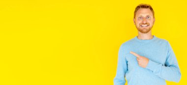 Gülümseyen adam parmak ile izole edilmiş arka planı kopyalama alanı ile işaret ediyor