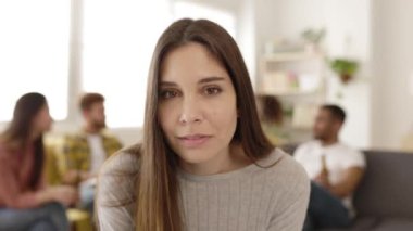 Genç ve güzel bir kadın kameraya gülümsüyor. Evde arkadaşlarıyla duruyor.