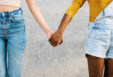 İki çok ırklı kadın el ele tutuşuyor.