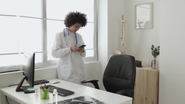 Mladá žena lékař pomocí svého mobilního telefonu na klinice — Stock video