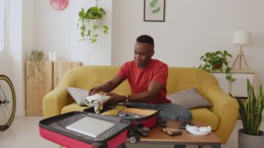 Genç Afrikalı bir adam yaz tatiline çıkmadan önce eşyalarını bavula topluyor.