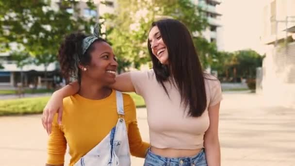 Zwei glückliche multiethnische Frauen lachen zusammen, während sie in der Stadtstraße spazieren gehen — Stockvideo