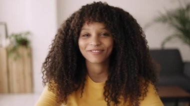 Mutlu Afrikalı genç Amerikalı kadın el sallıyor ve video konferansında kameraya konuşuyor. Video çağrısı ekran görüntüsü ve milenyum melez kadın konuşmalarının ve kahkahalarının kamera görüntüsü 