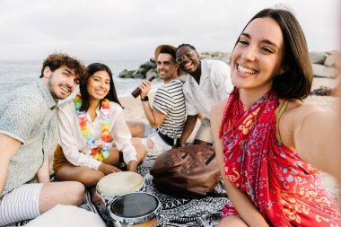 Sahilde rahatlarken selfie çeken bir grup genç arkadaş yaz tatilinde birlikte eğleniyorlar.