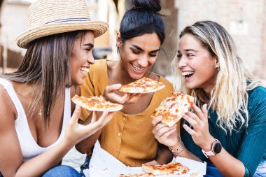 İtalya 'da yaz tatilinde pizza yiyen üç farklı ırktan genç kadın. Avrupa 'da seyahat ederken eğlenen genç kızlarla kadın arkadaşlığı kavramı. Tatiller ve İtalyan yemekleri konsepti