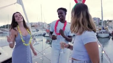 Yaz tatilinde yelkenlide dans eden bir grup çok kültürlü genç arkadaş - çeşitli insanlar hafta sonları parti yaparken eğleniyor - yüksek kaliteli FullHD görüntüleri