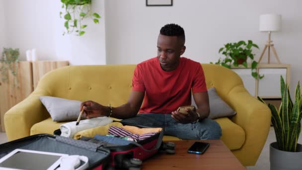 Νεαρός Ενήλικας Άνδρας Που Πακετάρει Ρούχα Στη Βαλίτσα Και Γράφει — Αρχείο Βίντεο