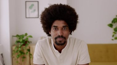 Afro saç stili mutlu milenyum erkeğinin portresi iş yerinde otururken kameraya gülümseyen Afrikalı Amerikalı adamın görüntüsü.