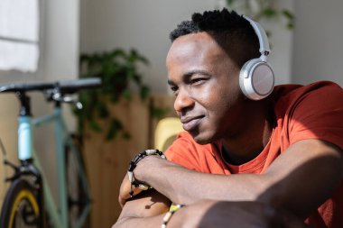 Afrikalı genç adam evdeki kanepede dinlenirken müzik dinlerken bin yıllık düşünceli bir adam pencereden içeri dalmayı düşünüyor.