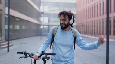 Mutlu genç girişimci kulaklıklı işçi, iş gününden sonra dans ederken müzik dinliyor. Mutluluk ve başarı kavramı.