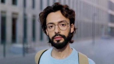 Kameraya bakan başarılı profesyonel serbest çalışan adam. Şehir sokağında dikilen sakallı bir gencin yavaş çekim portresi. Yüksek kalite 4k görüntü