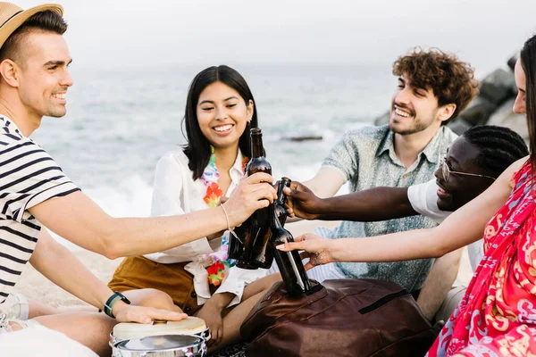 Multiracial friends cheering with beer at summer party at beach