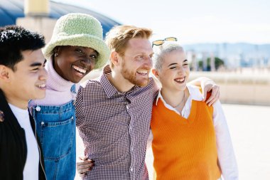 United group of multiracial young people hugging and embracing together outdoor - African american woman smiling at camera while standing with diverse friends in city street - Focus on african woman