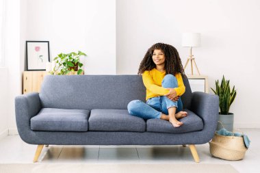 Relaxed smiling afro american woman sitting on sofa at home - Happy people and domestic lifestyle concept