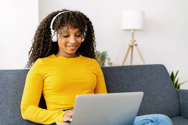 Cheerful afro american freelancer woman using laptop on sofa