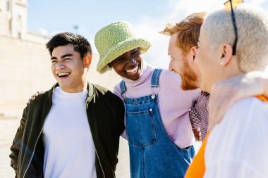 Happy multi ethnic group of young friends having fun together outdoors - Diverse men and women laughing in city street