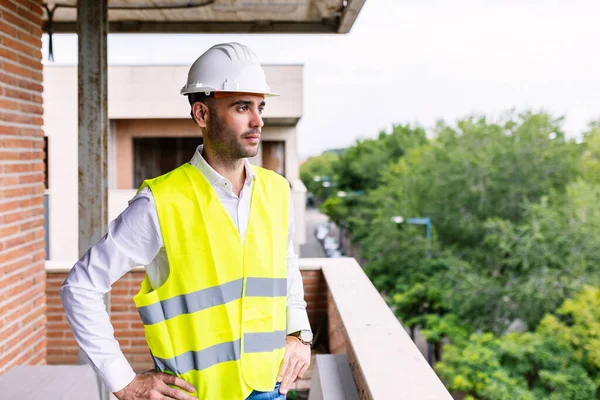 Young confident smart civil architect engineer standing on apartment construction site