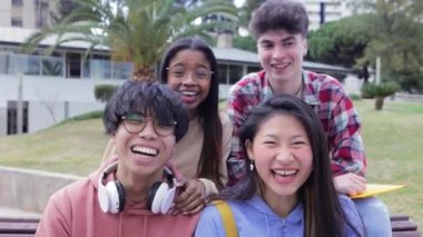 Multiracial group of millennial student friends portrait smiling at camera while sitting outdoors