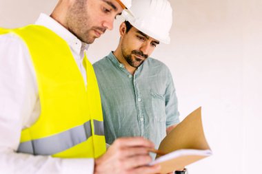 Young architect worker discussing with contractor male at construction building site
