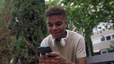Smiling millennial afro american man having fun watching funny videos on social media network app in mobile phone. Slow motion high quality 4k footage