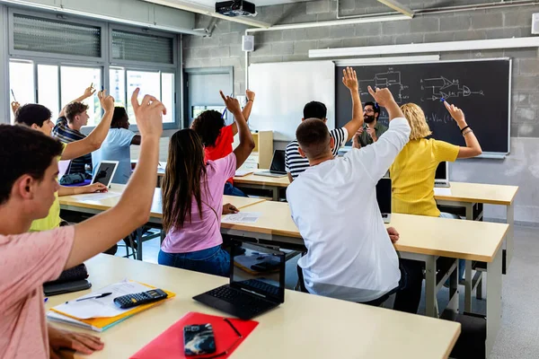 Group of high school students raising hands in classroom - Education concept