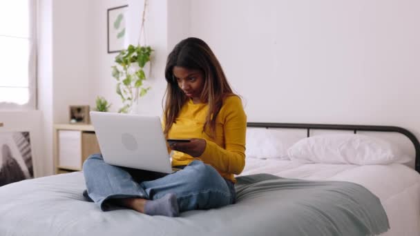 100万人のアフリカ系アメリカ人女性がクレジットカードを使ってオンラインショッピングをしている ラップトップコンピュータ上のクレジットカードでオンライン決済を行う若い女の子 高品質4K映像 — ストック動画